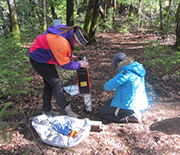 Two female researchers measuring water in bedrock.